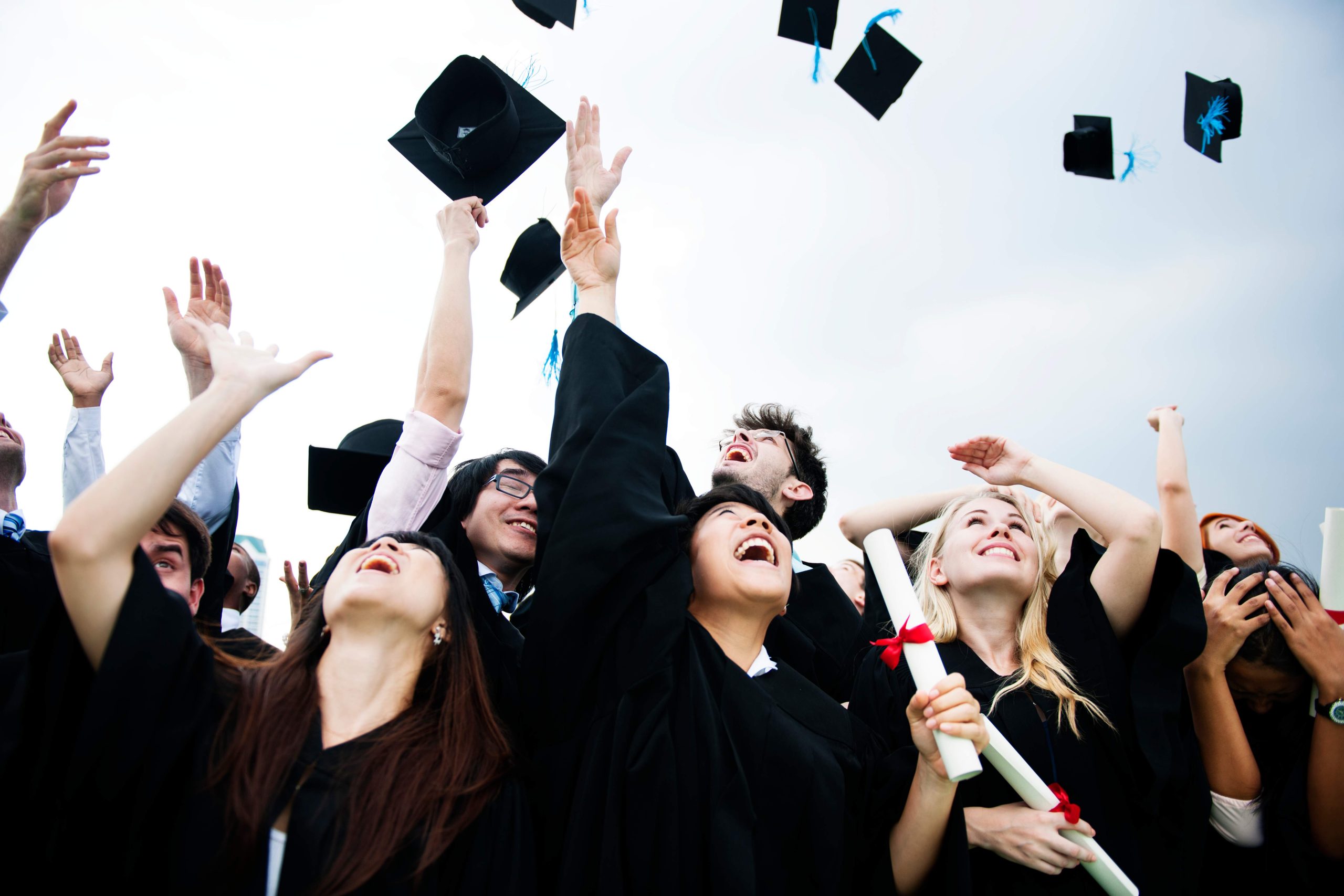 group-diverse-grads-throwing-caps-up-sky_11zon